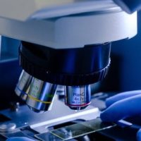 laboratory worker working with modern microscope while conducting coronavirus research 1 e1754467830809
